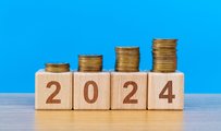4 wooden blocks spelling out '2024' with piles of coins on top of them