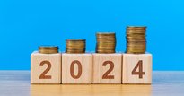 4 wooden blocks spelling out '2024' with piles of coins on top of them