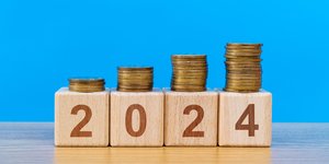4 wooden blocks spelling out '2024' with piles of coins on top of them