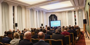 Event hall with many people sat looking at a screen