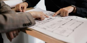 Two people reviewing architectural floor plans while planning a residential housing design