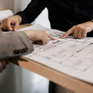 Two people reviewing architectural floor plans while planning a residential housing design