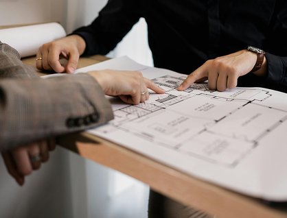 Two people reviewing architectural floor plans while planning a residential housing design