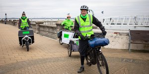 Three people on bikes with high vis on, operating a low carbon courier service