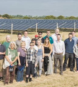 Group of people stood infront of a solar panel