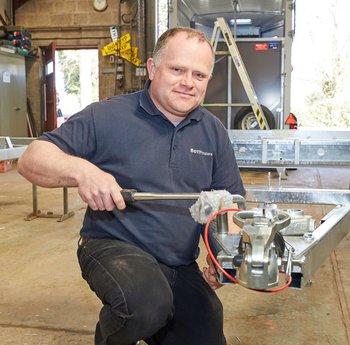 Man working on an axel for a trailer