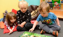 Three young children sitting and reading a book