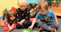 Three young children sitting and reading a book