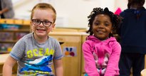 A young boy and young girl smiling in a classroom