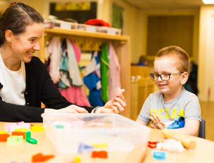 Young boy sitting in a classroom with a teacher