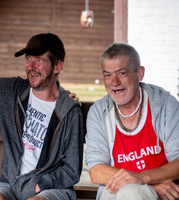 Three men sitting on a bench smiling and laughing