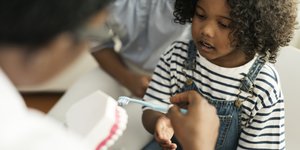 Young girl learning to brush teeth