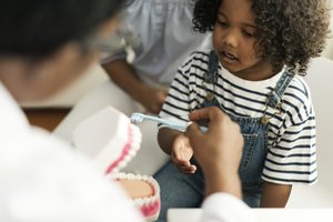 Young girl learning to brush teeth