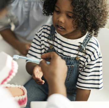 Young girl learning to brush teeth