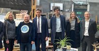 Six people, including Ed Miliband MP, at a scrap works smiling to the camera