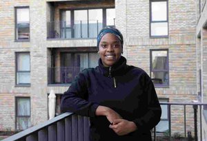 A tenant at the Campbell Wharf development standing on a balcony smiling at the camera