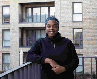 A tenant at the Campbell Wharf development standing on a balcony smiling at the camera