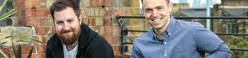 Two men sat on a bench smiling