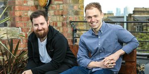 Two men sat on a bench smiling
