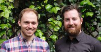 Two men smiling infront of a green bush