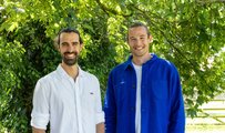 Two men in smart casual clothing standing in front of a tree, smiling