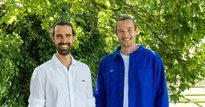 Two men in smart casual clothing standing in front of a tree, smiling