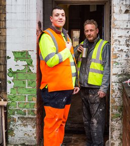 Two men wearing high visibility jackest standing in a doorway