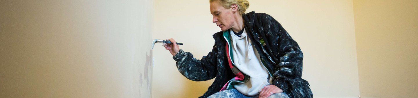 Woman sat on floor painting a wall
