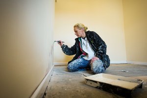 Woman sat on floor painting a wall