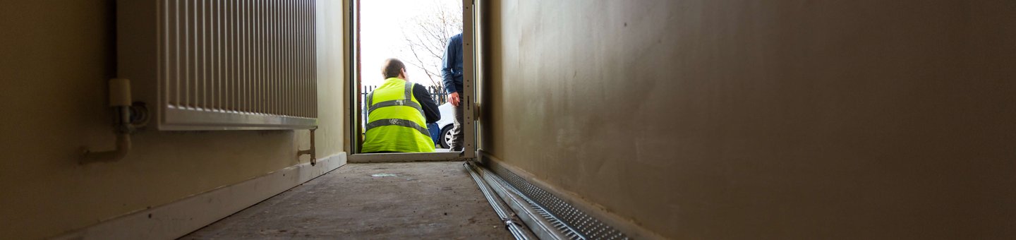 Man wearing a high visibility jacket sitting in a hallway