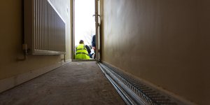 Man wearing a high visibility jacket sitting in a hallway