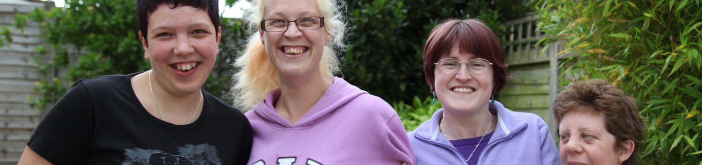 Four women smiling and linking arms