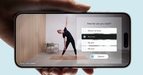 Hand holding a smartphone, showing an app interface where a woman is doing a yoga pose