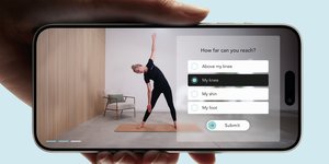 Hand holding a smartphone, showing an app interface where a woman is doing a yoga pose