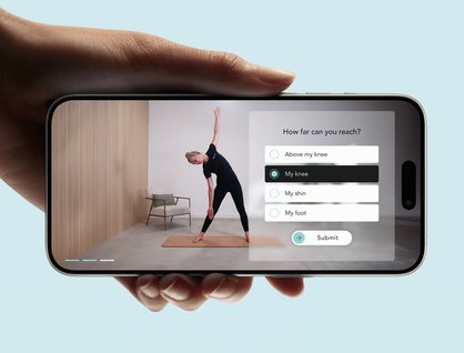 Hand holding a smartphone, showing an app interface where a woman is doing a yoga pose
