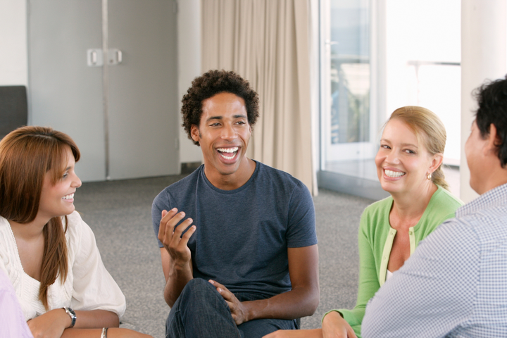Five people sat in a circle, with the central one speaking