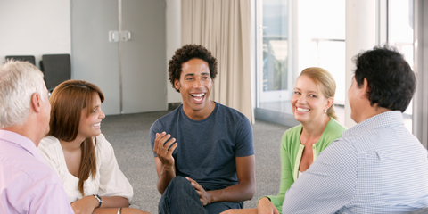 Five people sat in a circle, with the central one speaking