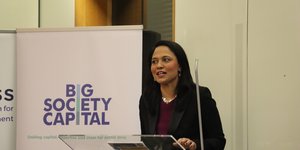 Rushanara Ali MP speaking at a lectern in front of a pop up banner which says 'Big Society Capital - Uniting capital, expertise and ideas for better lives'