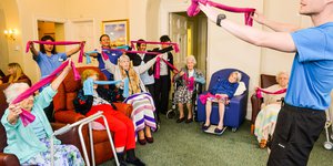 A room of elderly women exercising on chairs