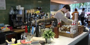 Worker at social enterprise cafe, Open Kitchen making coffee