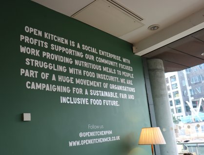 Green wall showing text which outlines Open Kitchen's work