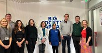 Members of BSC standing with a member of Clean for Good's staff in front of the organisation's logo