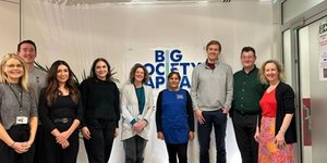 Members of BSC standing with a member of Clean for Good's staff in front of the organisation's logo