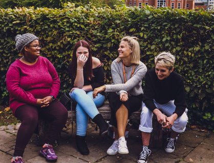 Three women sitting on a bench laughing