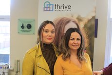 Two women smiling in front of a thrive women's aid pop up banner