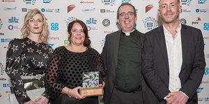Three people standing holding an award