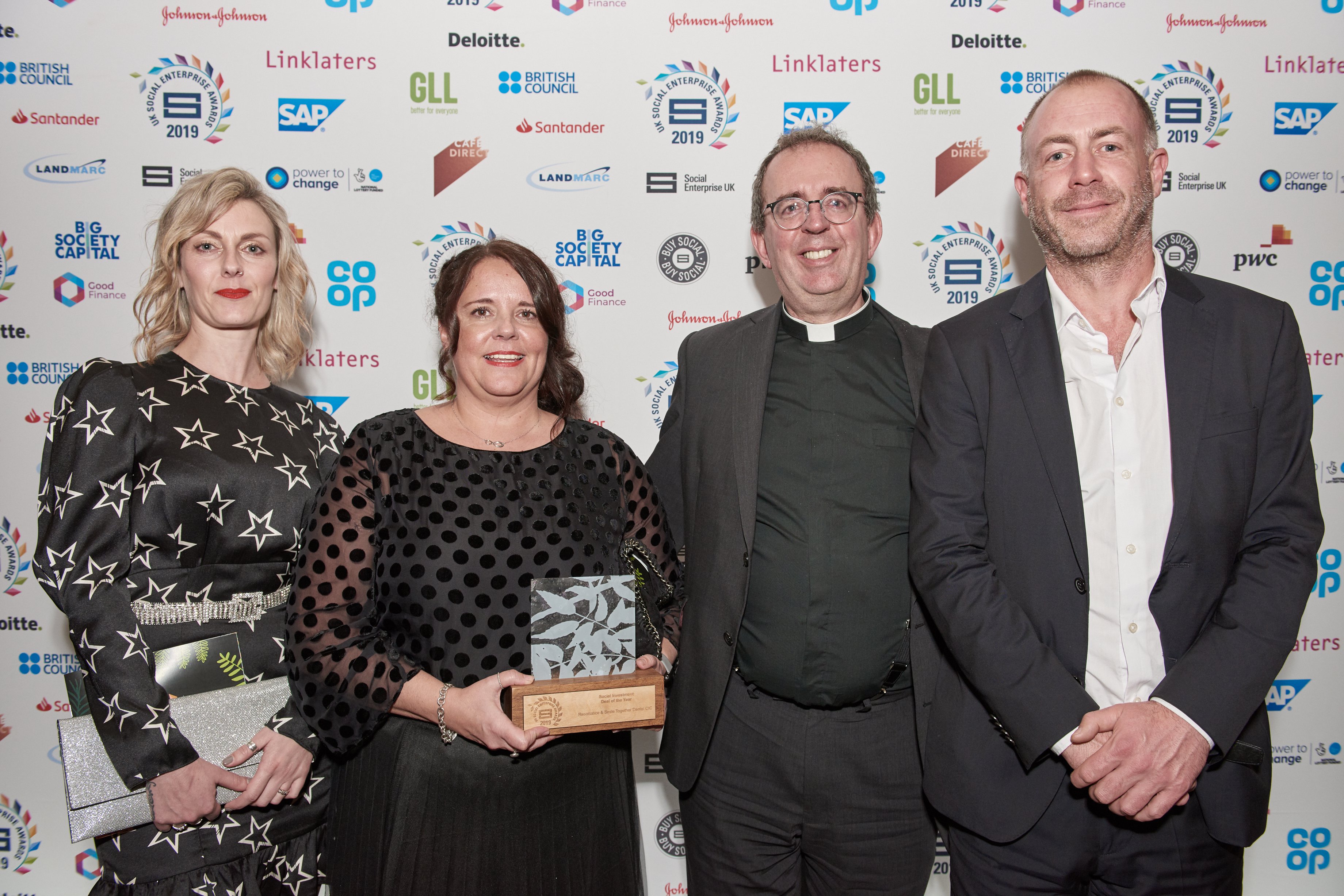 Three people standing holding an award