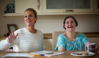 A woman with a learning disability smiling with their carer
