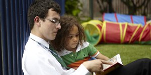 Man reading a book with a child