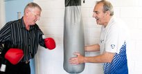 Two elderly men boxing with gloves and a punching bag
